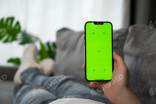 Preview: Man lying on the sofa with smartphone in his hands with green chroma screen. Food delivery app