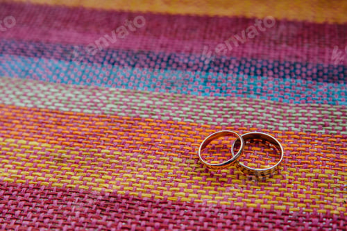 Preview: Two golden wedding rings on colourful fabric. Bridal accessories. Holiday, celebration