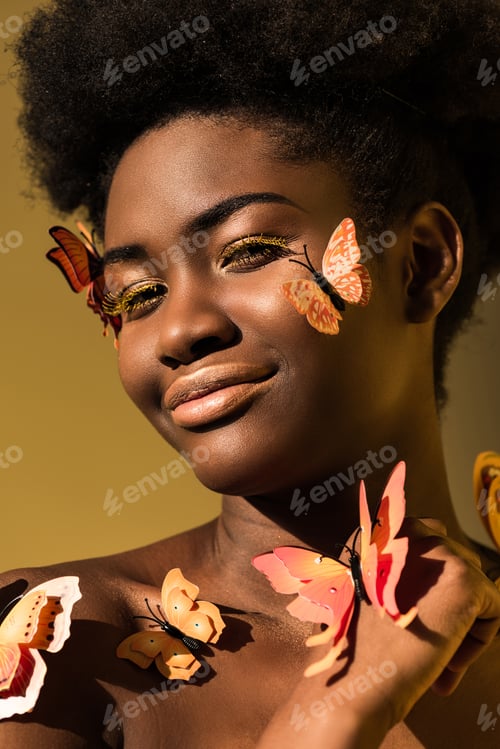 Preview: Smiling african american woman with butterflies isolated on brown