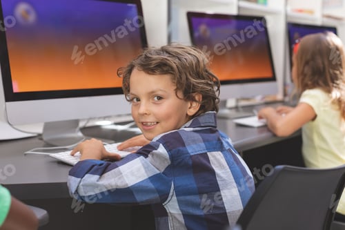 Preview: Portrait of happy caucasian schoolboy sitting and looking at camera in computer room