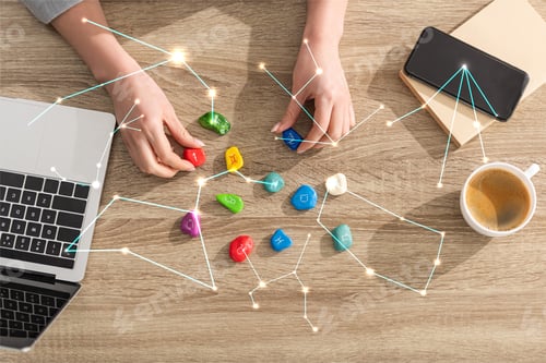 Preview: Top view of astrologer holding stones with zodiac sign beside laptop, coffee and constellations