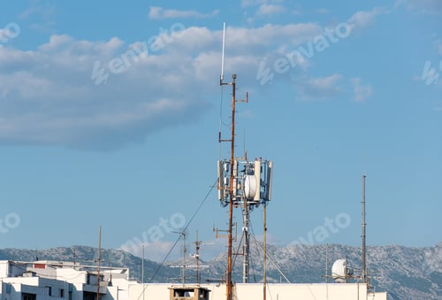 Preview: Cluster of mobile network broadcast cell repeaters on roof of building in city.