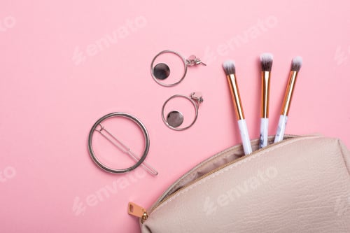 Preview: Women's cosmetic bag with makeup brushes and earrings on a pink background