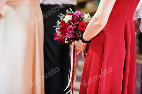 Preview: Wedding bouquets at hands of bridesmaids stay on church ceremony.