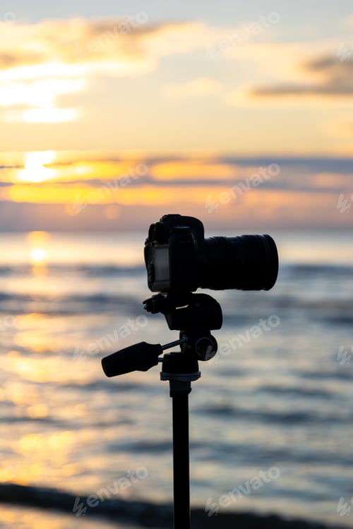 Preview: Camera on tripod with handle above waves at golden hour. Camera on beach.
