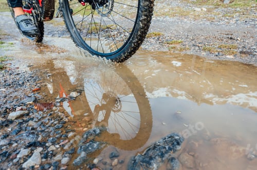 Preview: Man riding a mountain bike passing a puddle of water