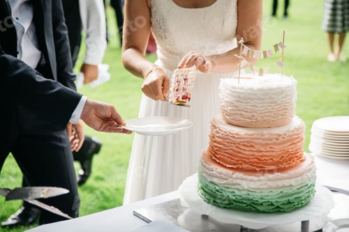 Preview: Bride and groom cutting a piece of orange three tiered outdoors