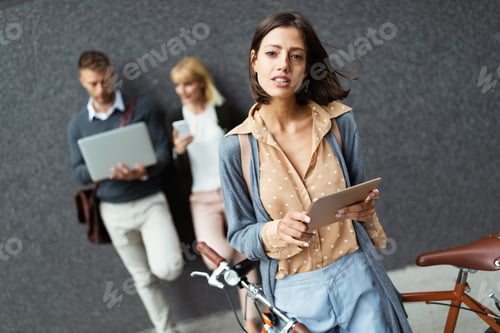 Preview: Group of happy young business people holding different digital devices outdoor