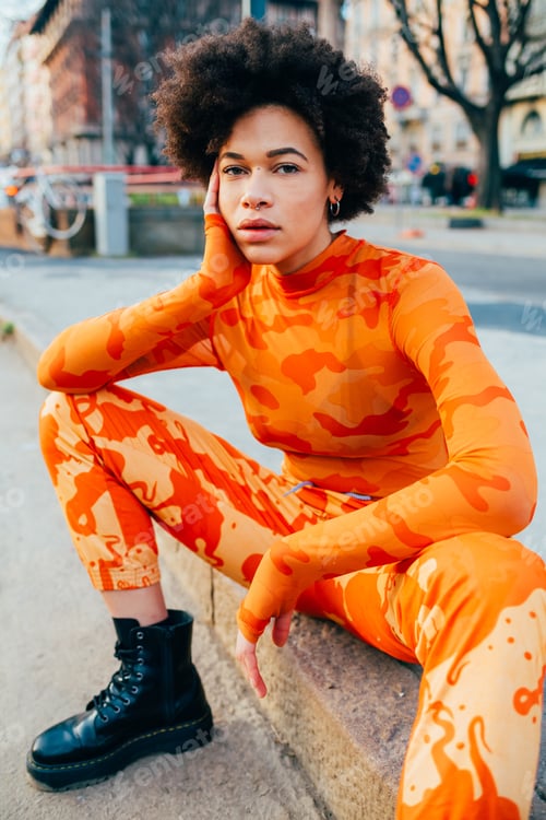 Preview: Trendy curly hair black woman posing outdoor looking camera contemplative