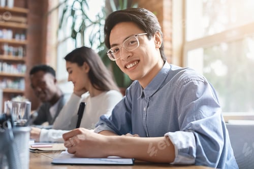 Preview: Smiling asian guy taking notes while business meeting with colleagues