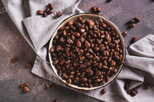 Preview: Close up of ripe pine nuts in the shells on a plate on the table top view