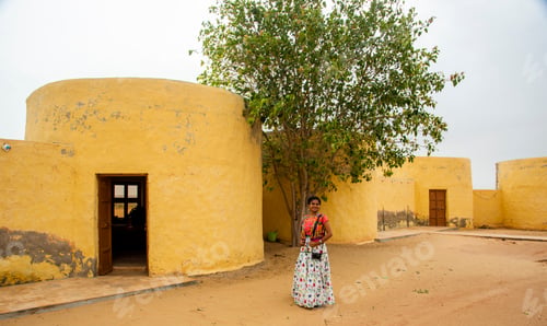 Preview: Woman in front of desert house, India.