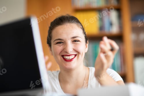 Preview: Young woman with a beaming smile working on her laptop at home