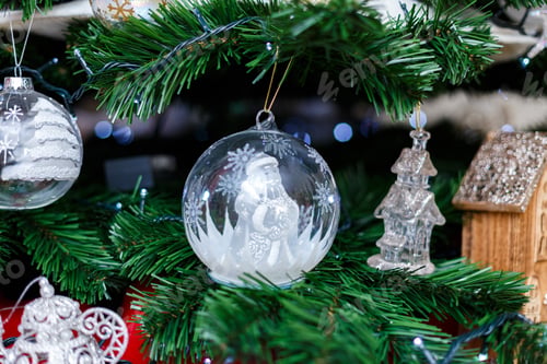 Preview: Christmas tree decorations on an artificial fir tree. Glass baubles, wooden houses and blue lights.