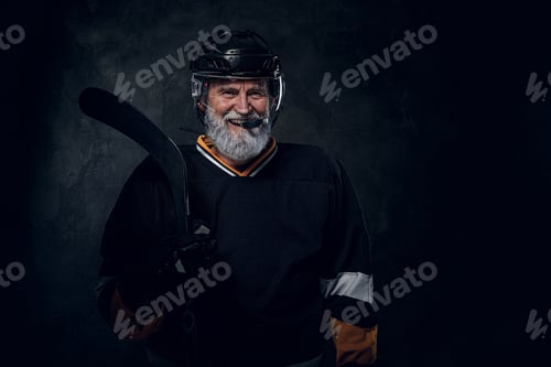 Preview: Joyful elderly hockey player with hockey stick dressed in uniform