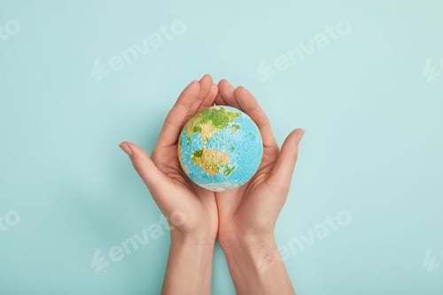 Preview: top view of woman holding planet model on turquoise background, earth day concept