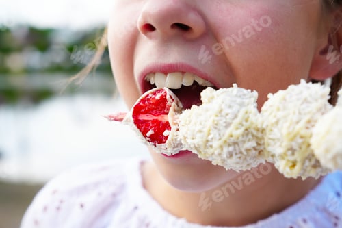 Preview: Beautiful girl eating a fresh red strawberry in white chocolate