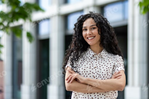Preview: Confident businesswoman standing with arms crossed in front of corporate building