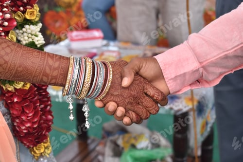 Preview: Closeup shot of the Indian couple's hands holding, during their wedding