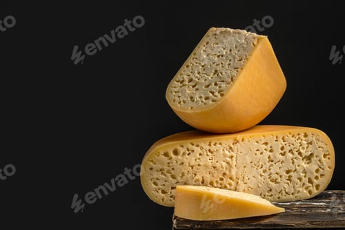 Vista previa: french hard cheese with holes emmentaler on a dark background. Long banner format