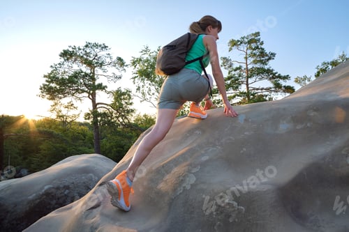 Preview: Hiker woman clambering on rocky mountain footpath in evening nature.