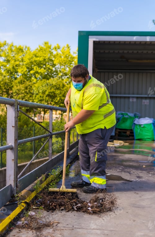 Preview: Worker in a recycling factory or clean point and garbage with a face mask