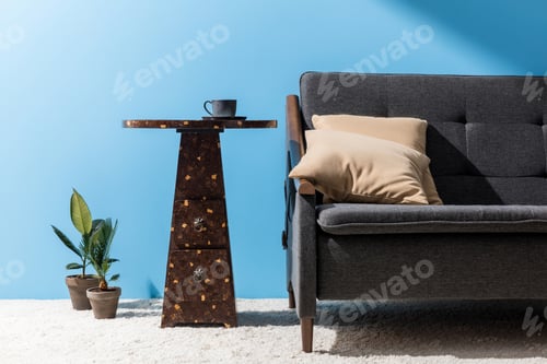 Preview: coffee table with cup near couch in front of blue wall