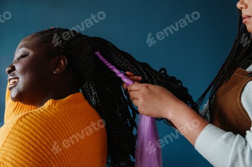 Preview: Close-up of hairdresser braiding hair to young smiling African woman