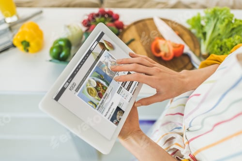 Preview: Woman Using Digital Tablet In Kitchen For Recipe