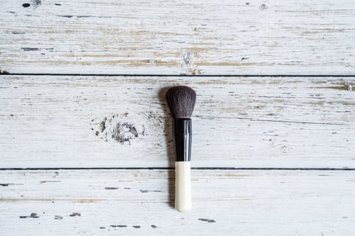 Preview: Makeup brush lying on white wooden background