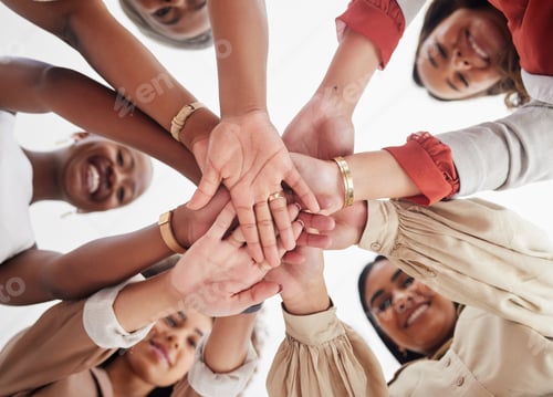 Preview: Low angle diverse group of ambitious smiling businesswomen huddled together with hands stacked in m