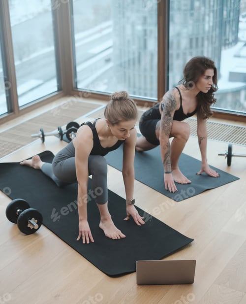 Preview: Girls do yoga workout on mats using a modern laptop in gym