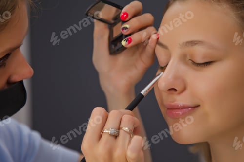 Preview: Female makeup artist makes up cute beautiful young woman in beauty salon