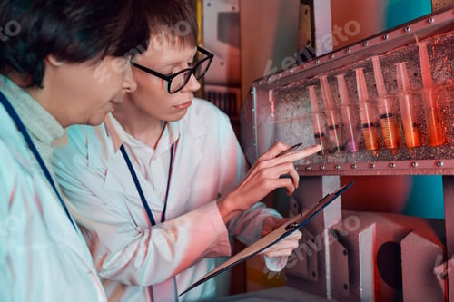 Preview: cosmic exploration, intern pointing at test tubes with extraterrestrial samples near woman scientist