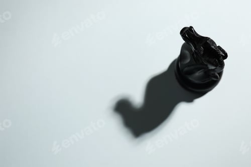 Preview: Black wooden chess knight on light grey background, above view. Space for text