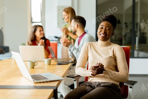 Preview: Cute Africam American woman with her young multiethnic startup team working in the modern office