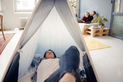 Preview: Woman resting in tent , while father is playing with their son in background