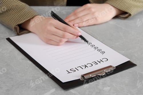 Preview: Woman filling Checklist at grey marble table, closeup
