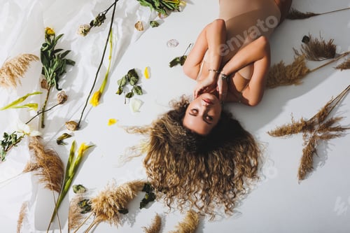 Preview: A slender woman in a beige jumpsuit poses next to dried flowers on a white isolated background.