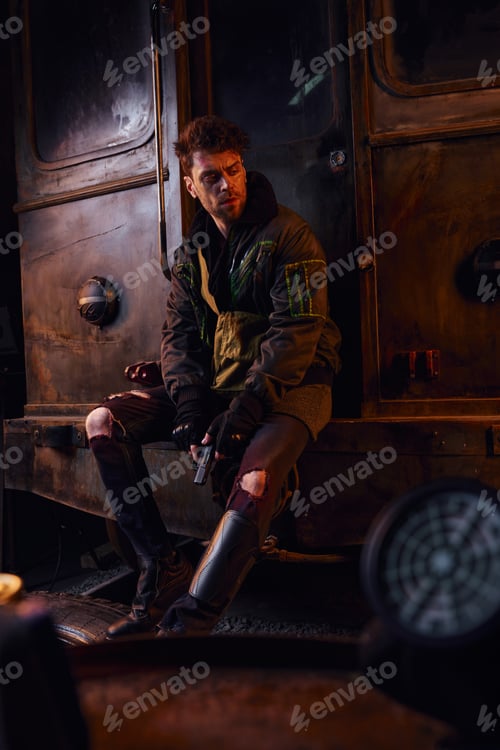 Preview: devastated man in worn clothes sitting with gun on rusty subway carriage, post-apocalyptic isolation