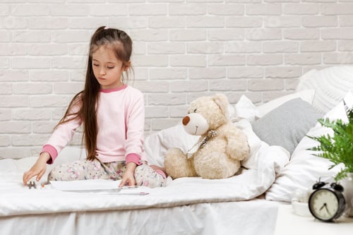 Preview: little girl drawing pictures while lying on bed.