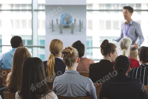 Preview: Group of business professionals attending a seminar with an male Asian speaker in office building