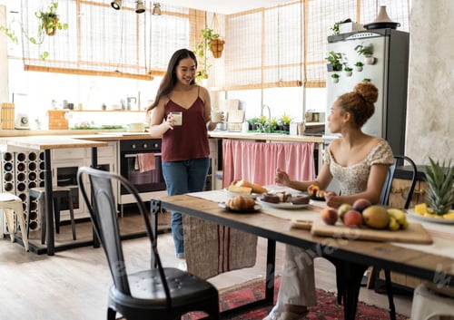 Preview: couple of young lesbian gay women are having breakfast together in the kitchen at home