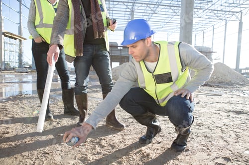 Preview: Builder and architects marking floor area with spray can on construction site
