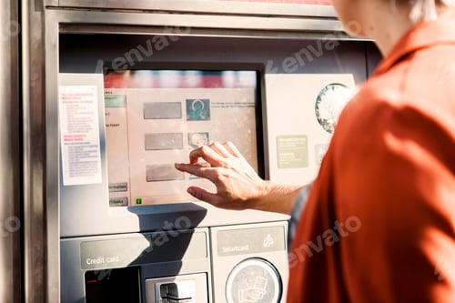 Preview: Midsection of businesswoman using ticket machine at railroad station