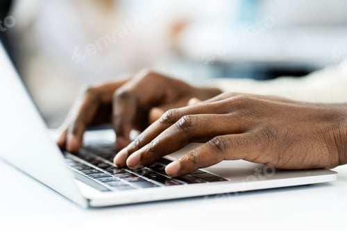 Preview: African American programmer writing code on laptop keyboard at workplace