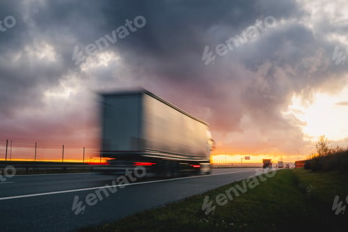 Preview: Motion blurred truck driving fast on highway at sunset