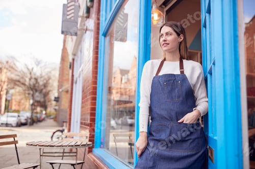 Preview: Smiling Female Small Business Owner Standing In Shop Doorway On Local High Street