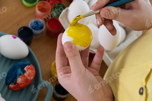 Preview: Easter. Cute smiling boy painting easter egg at home.