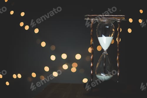 Preview: Closeup shot of a sand glass timer with blurred lights in the background